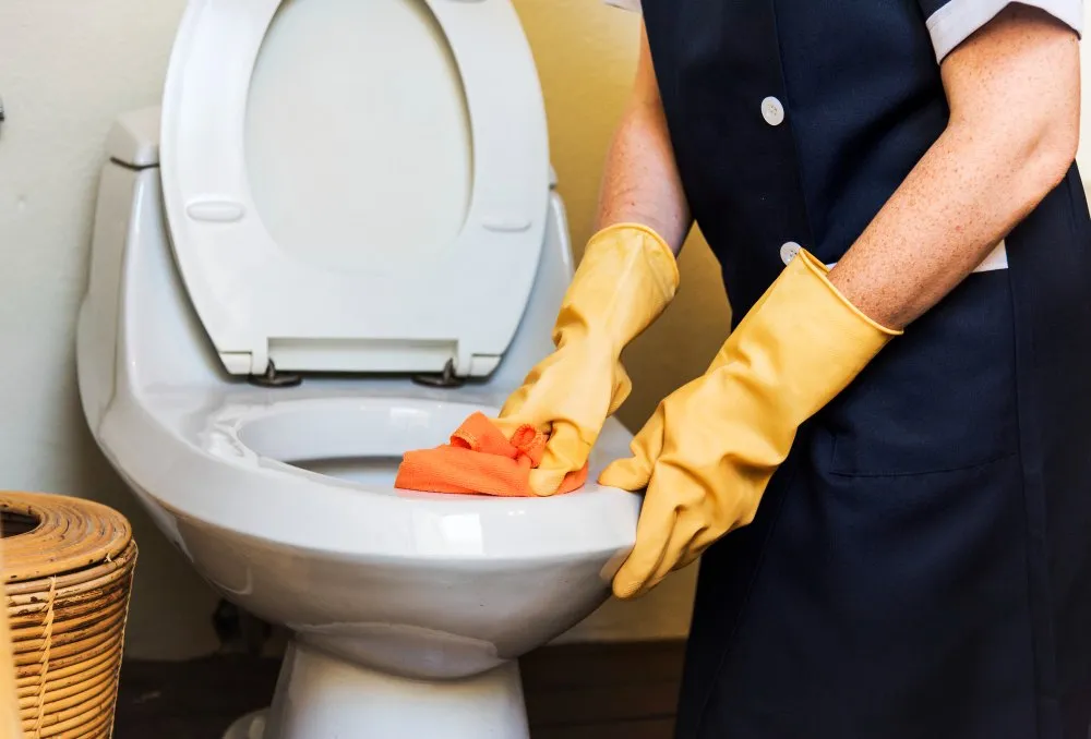 Person, die eine Toilette reinigt