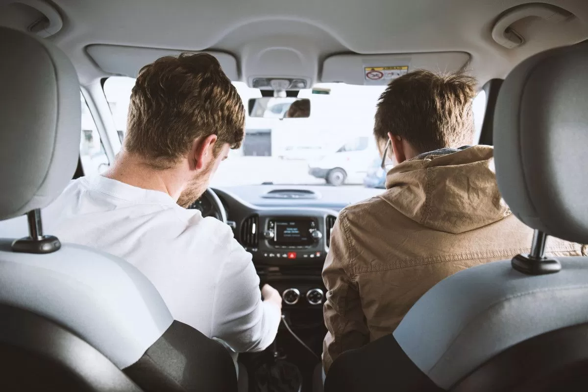 Twee mannen zitten voorin een auto.